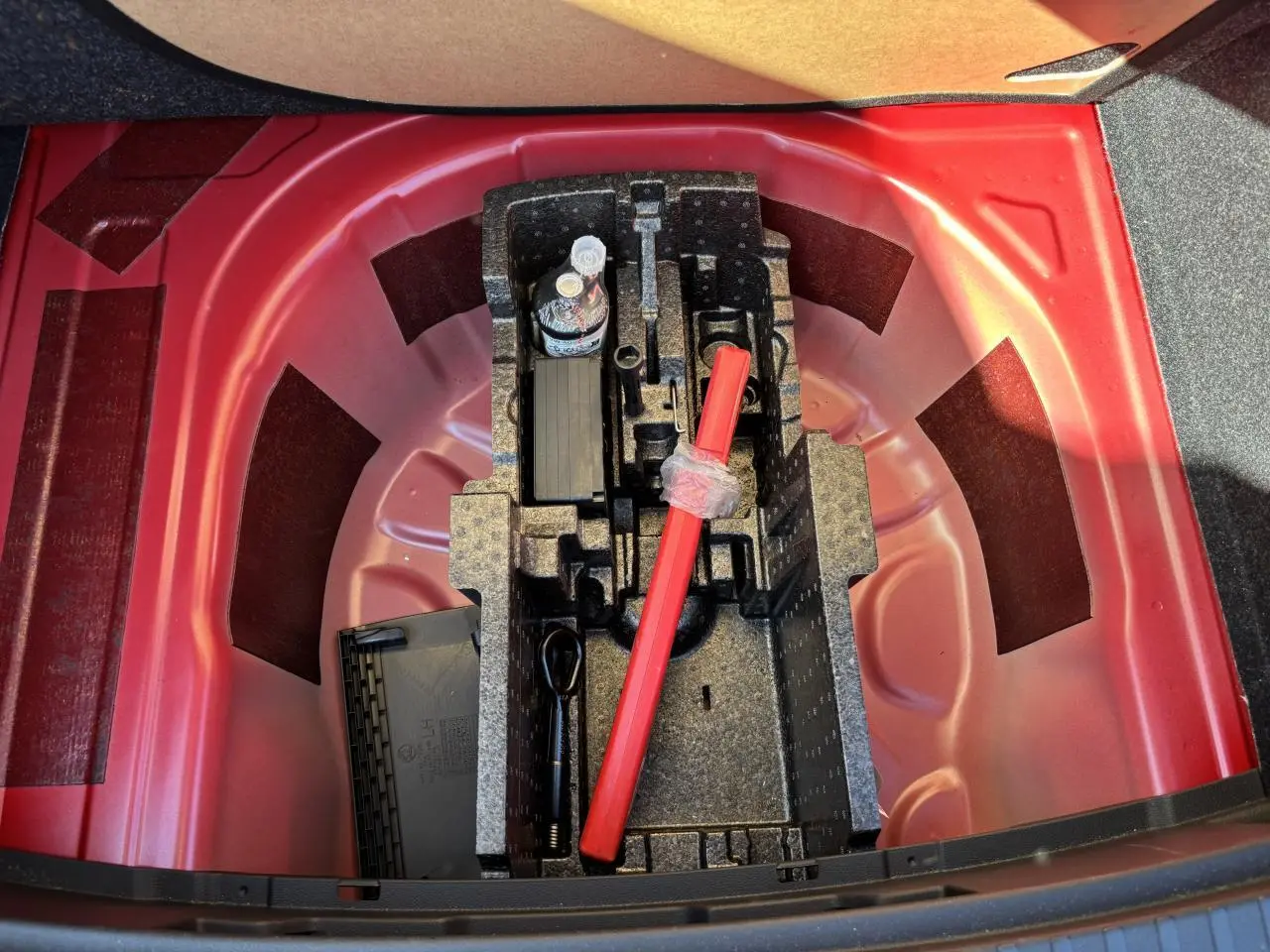Coffre ouvert montrant le rangement sous plancher rouge velvet metal avec outils et triangle de sécurité SKODA SCALA 2024.