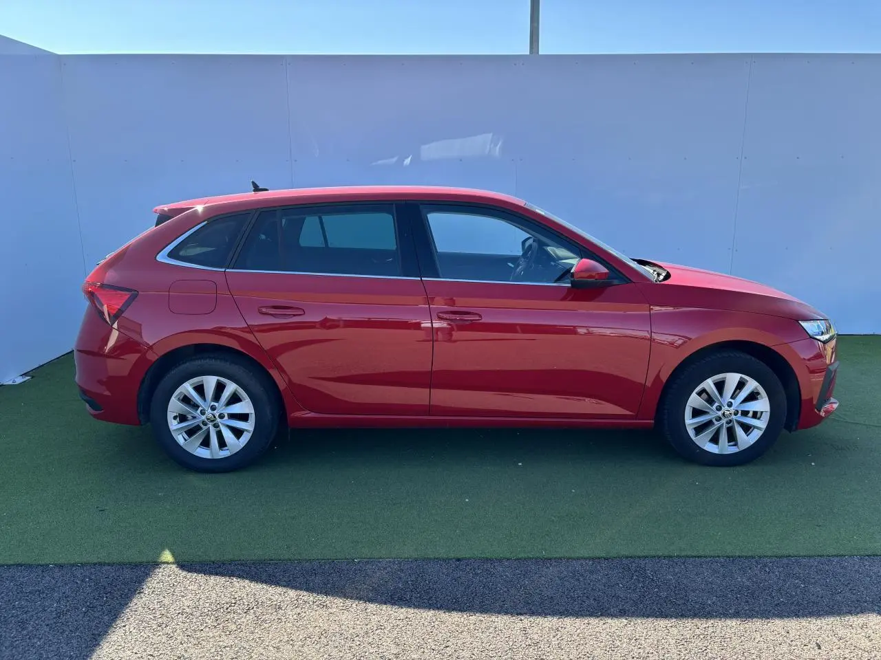 Profil côté gauche d'une Skoda Scala rouge Velvet Metal 2024 avec jantes alliage 16 pouces sur fond neutre.