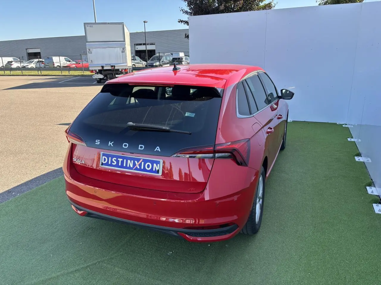 Vue 3/4 arrière droite d'une Skoda Scala rouge Velvet Metal avec feux arrière LED et logo distinctif sur fond urbain.