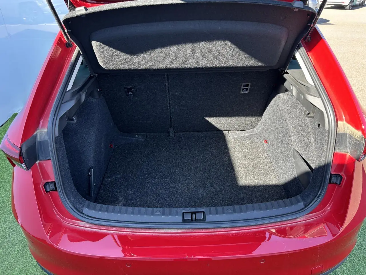 Coffre ouvert vu de l'arrière d'une Skoda Scala 2024 rouge Velvet Metal, montrant l'espace de chargement vide.