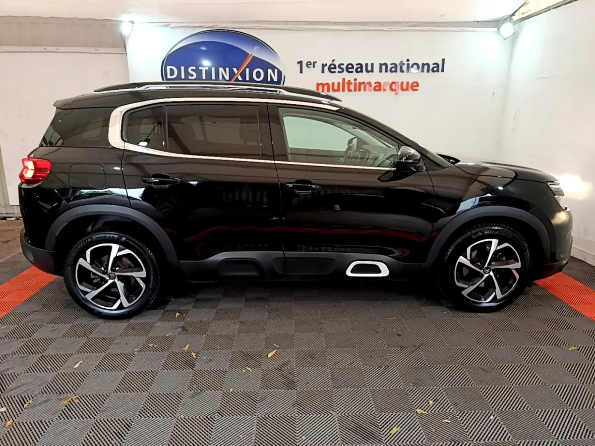 Profil droit d'un Citroën C5 Aircross noir 2020 avec jantes alliage et protections latérales blanches.