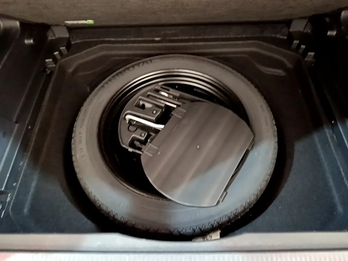 Vue plongeante sur la roue de secours noire et ses outils dans le coffre du Citroën C5 Aircross noir de 2020