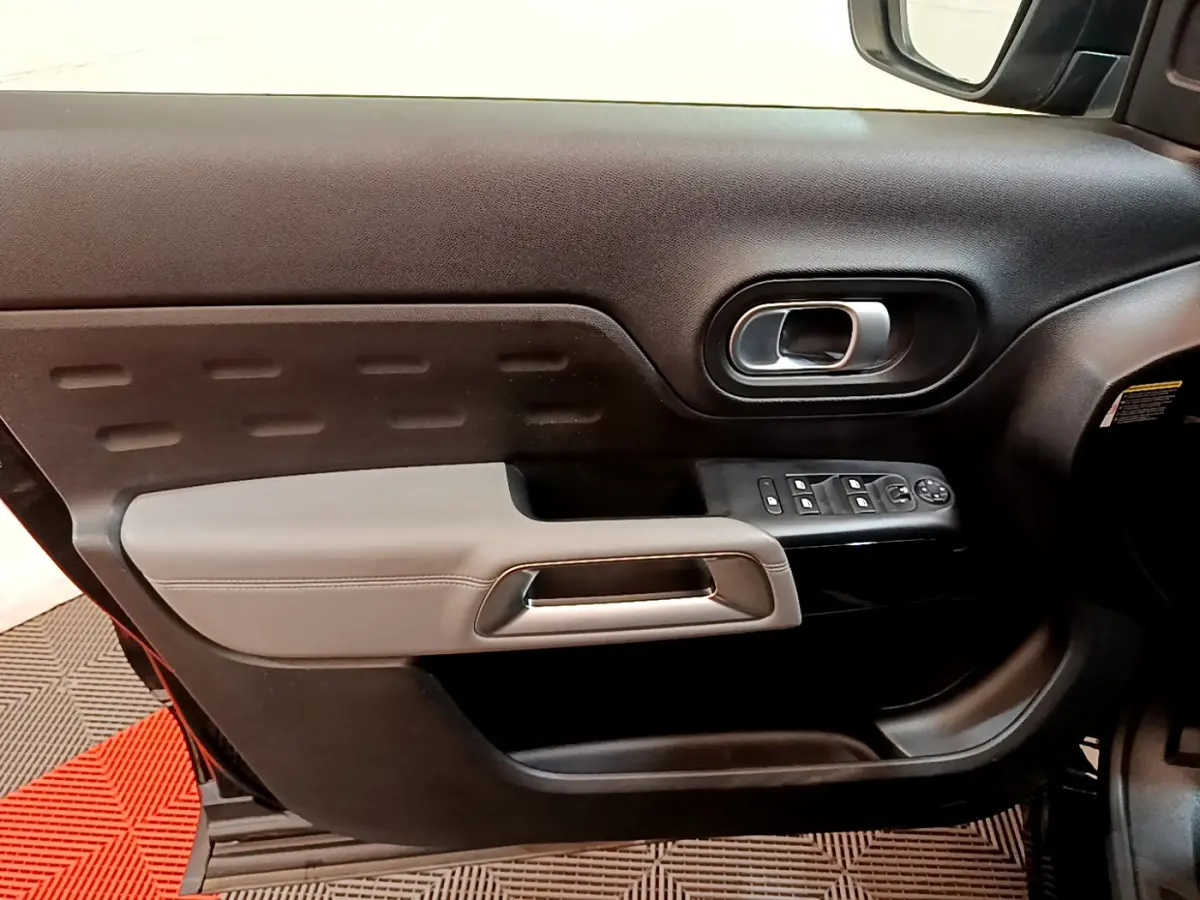 Intérieur côté gauche de la porte avant d'une Citroën C5 Aircross noire, avec commandes de vitres et poignée argentée.