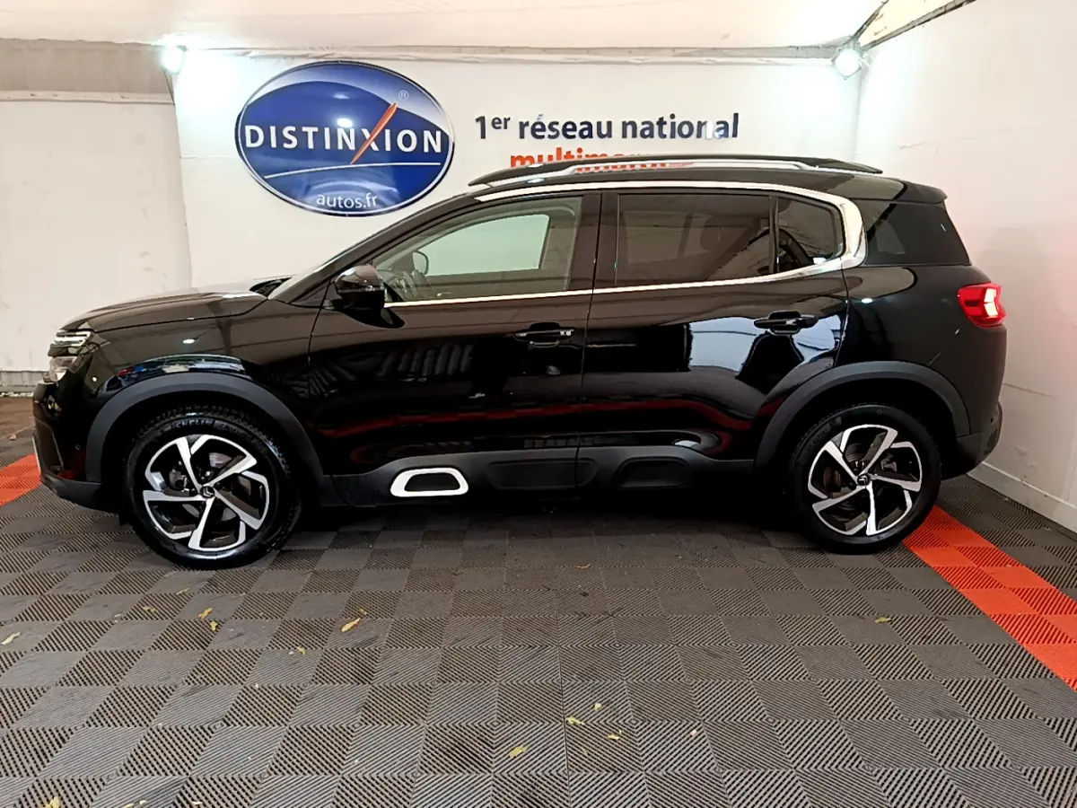 Profil côté gauche d'un SUV Citroën C5 Aircross noir 2020 avec jantes alliage et barres de toit visibles.