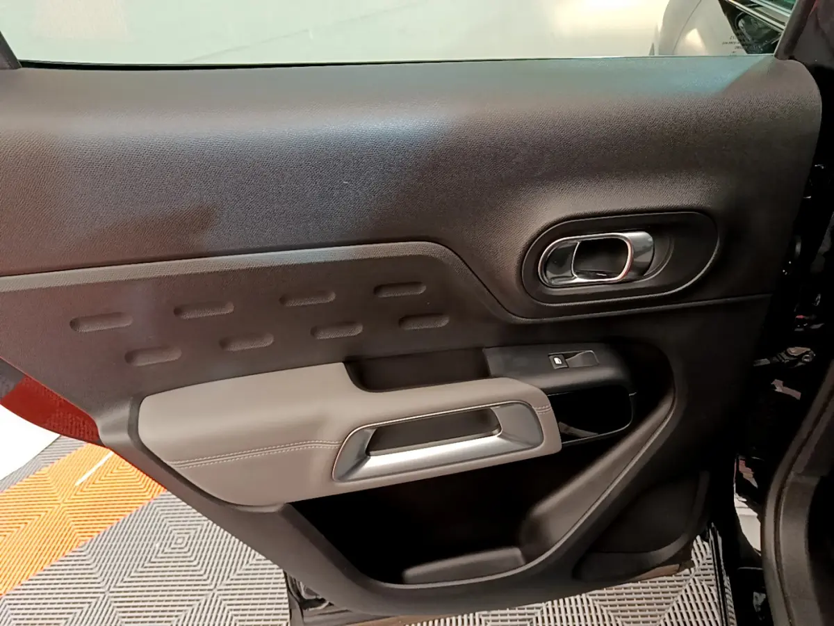 Gros plan sur la porte intérieure côté gauche du Citroën C5 Aircross noir, avec poignée argentée et garniture bicolore.