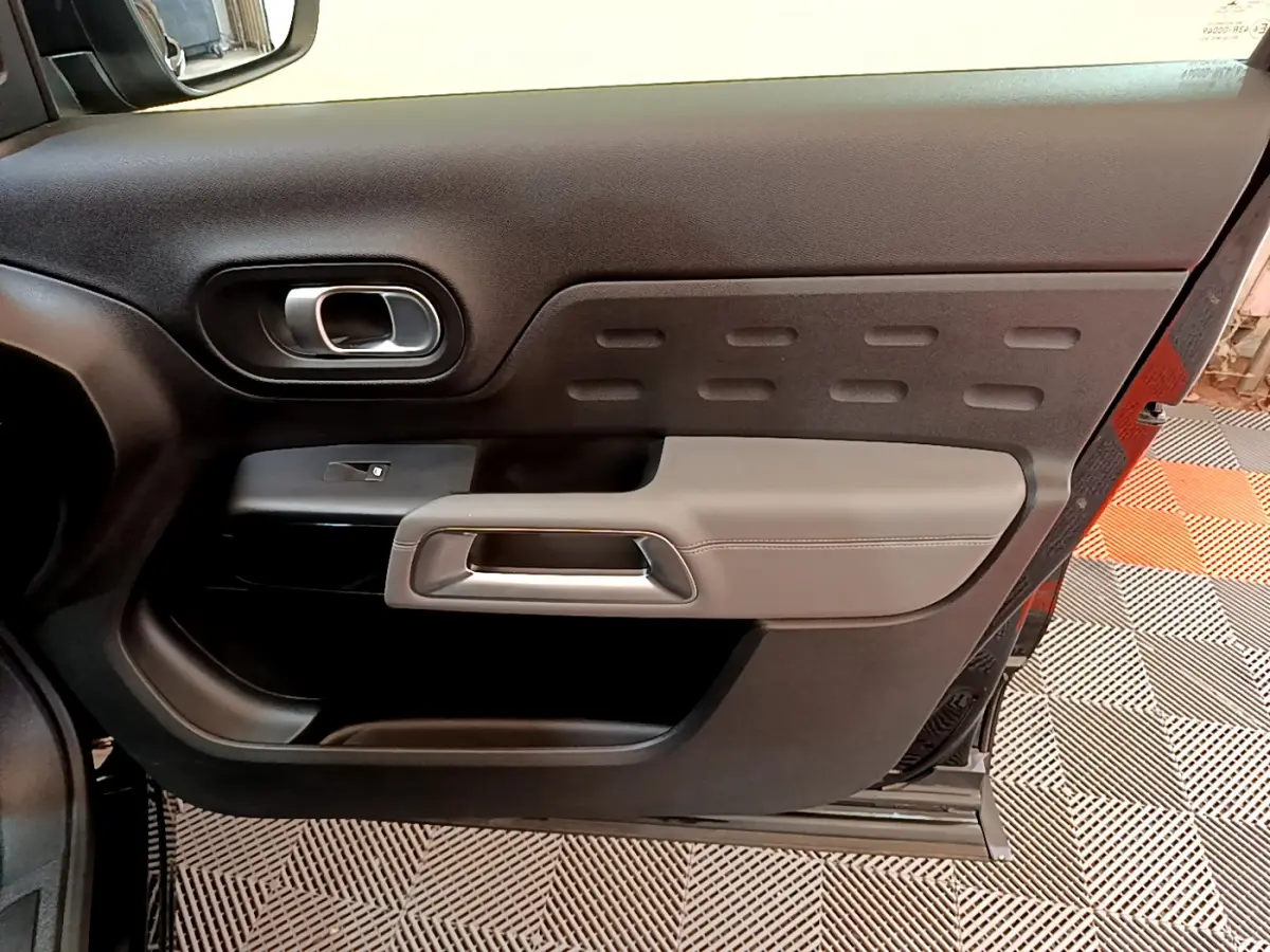 Vue rapprochée de la porte intérieure côté gauche du Citroën C5 Aircross noir, avec poignée argentée et garniture grise.