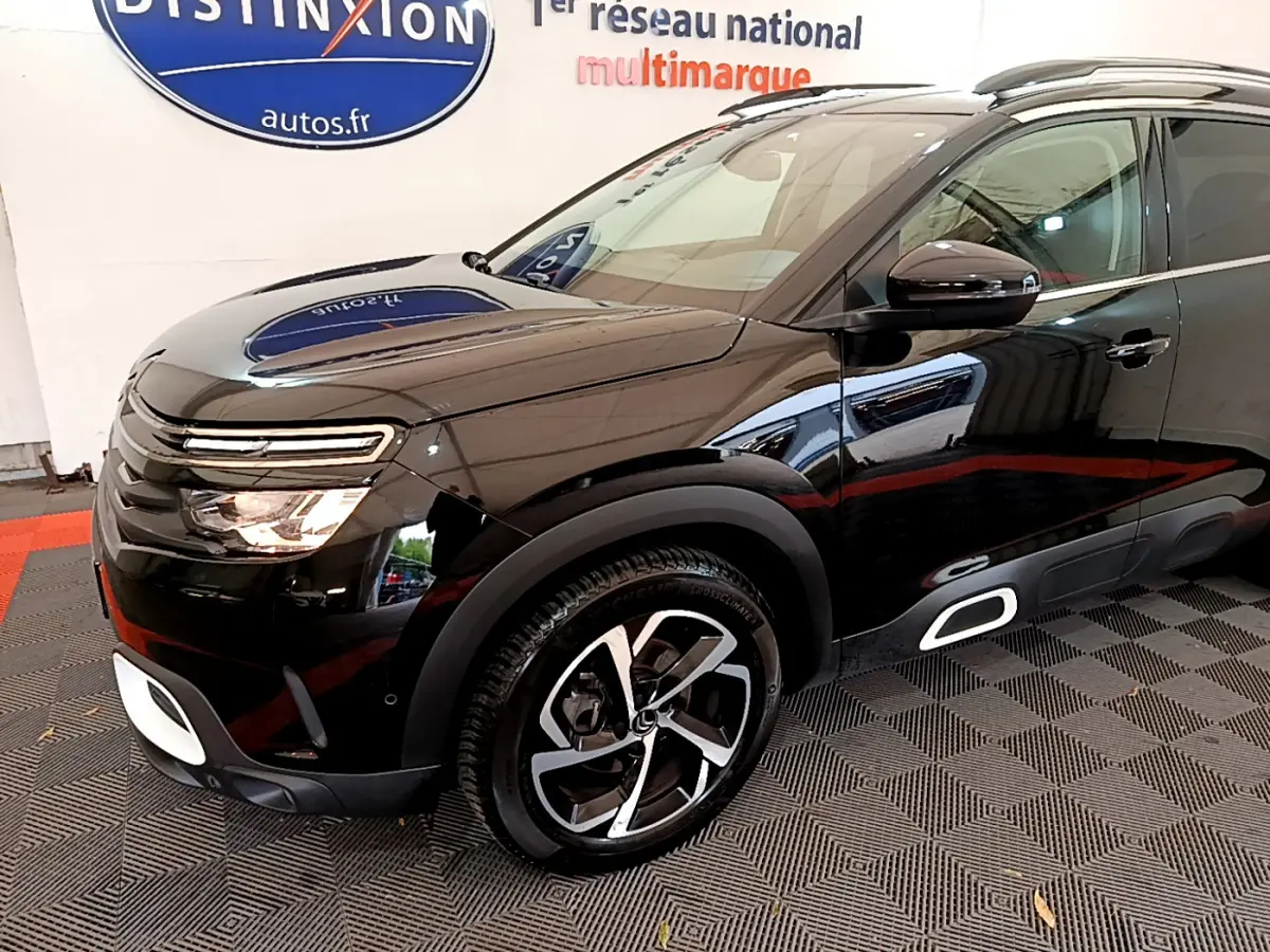 Vue 3/4 avant gauche d'un Citroën C5 Aircross noir avec jantes alliage et détails blancs sur le bouclier et bas de caisse.