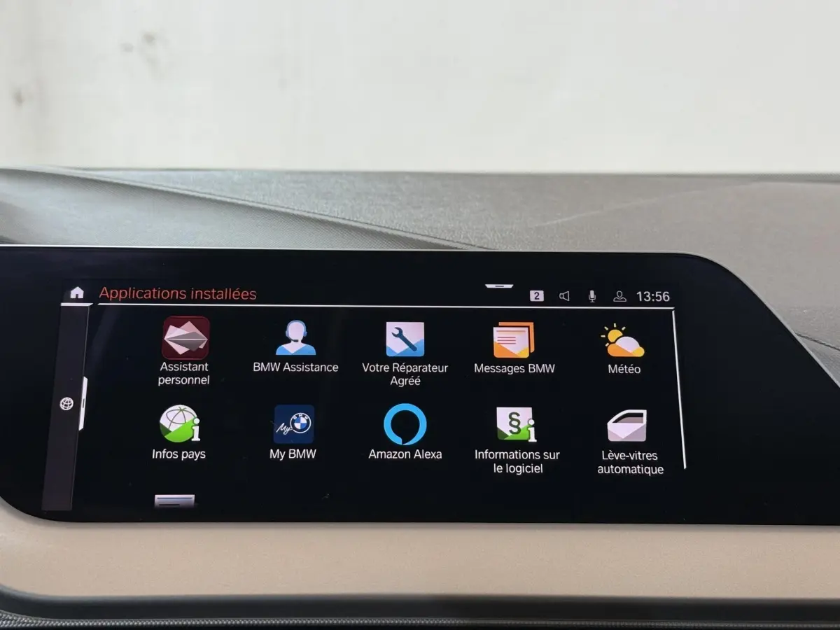 Écran tactile central affichant les applications connectées dans une BMW Série 1 116d Business Design, intérieur beige.