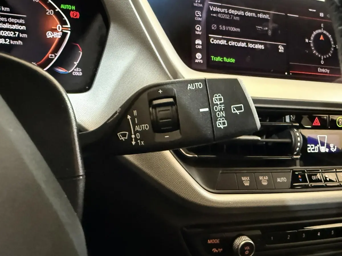 Gros plan sur la commande d’essuie-glace à gauche du volant dans l’habitacle noir et beige de la BMW Série 1 116d.