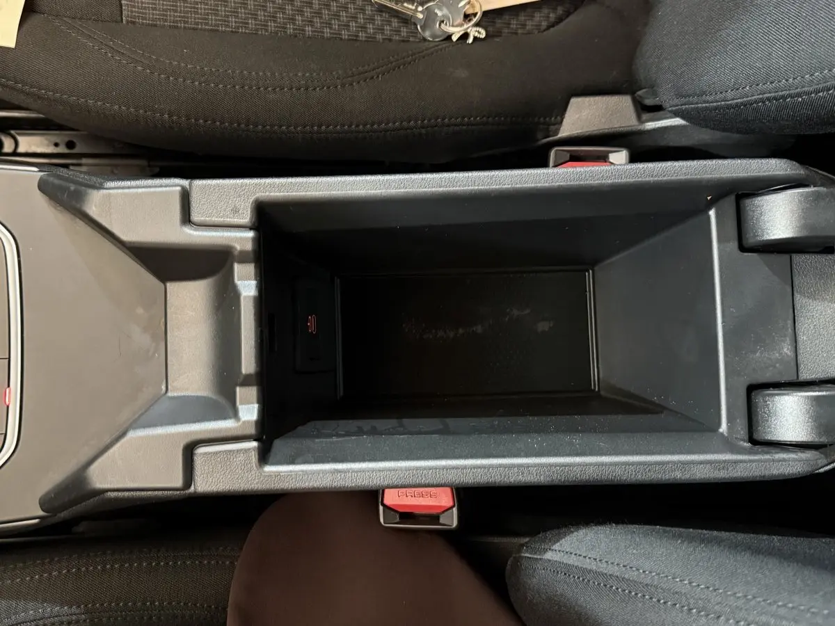 Vue plongeante sur le rangement central noir entre les sièges avant d'une BMW Série 1 116d Business Design 2022.