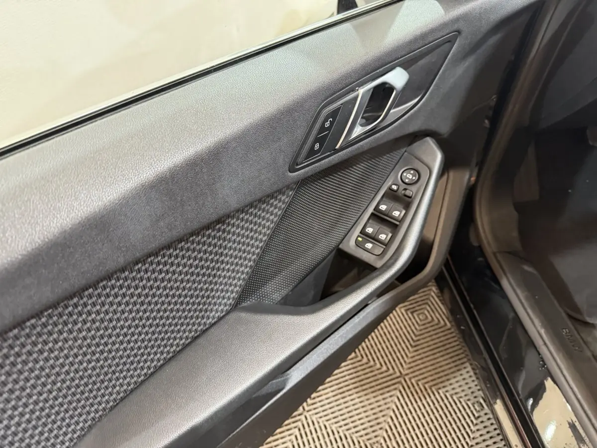 Vue rapprochée de la porte avant gauche noire de la BMW Série 1 116d avec commandes électriques et poignée argentée.