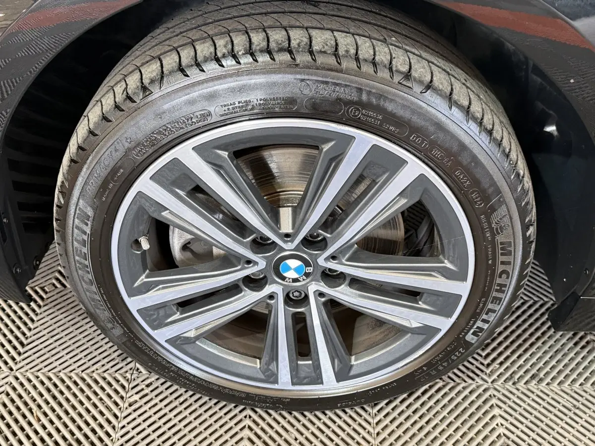 Gros plan sur la jante alliage grise et noire d’une BMW Série 1 116d, avec pneu Michelin visible.