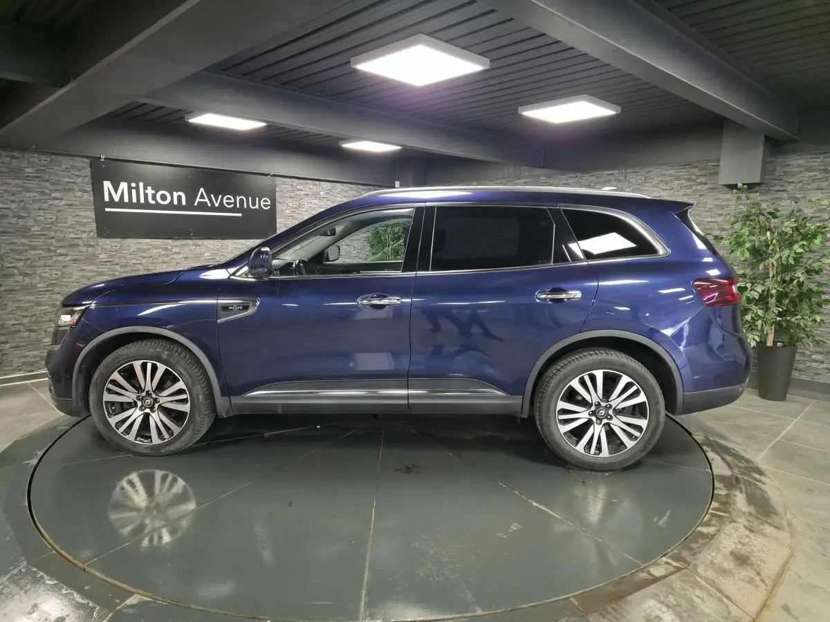 Renault Koleos bleu de Saxe vu de profil côté gauche, avec jantes alliage 19 pouces et vitres teintées.