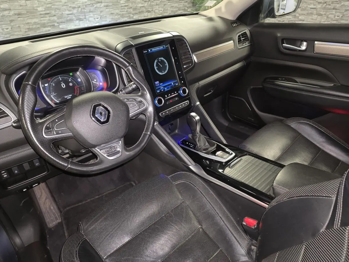 Vue intérieure côté conducteur du Renault Koleos bleu, avec volant cuir Initiale Paris et écran tactile vertical central.