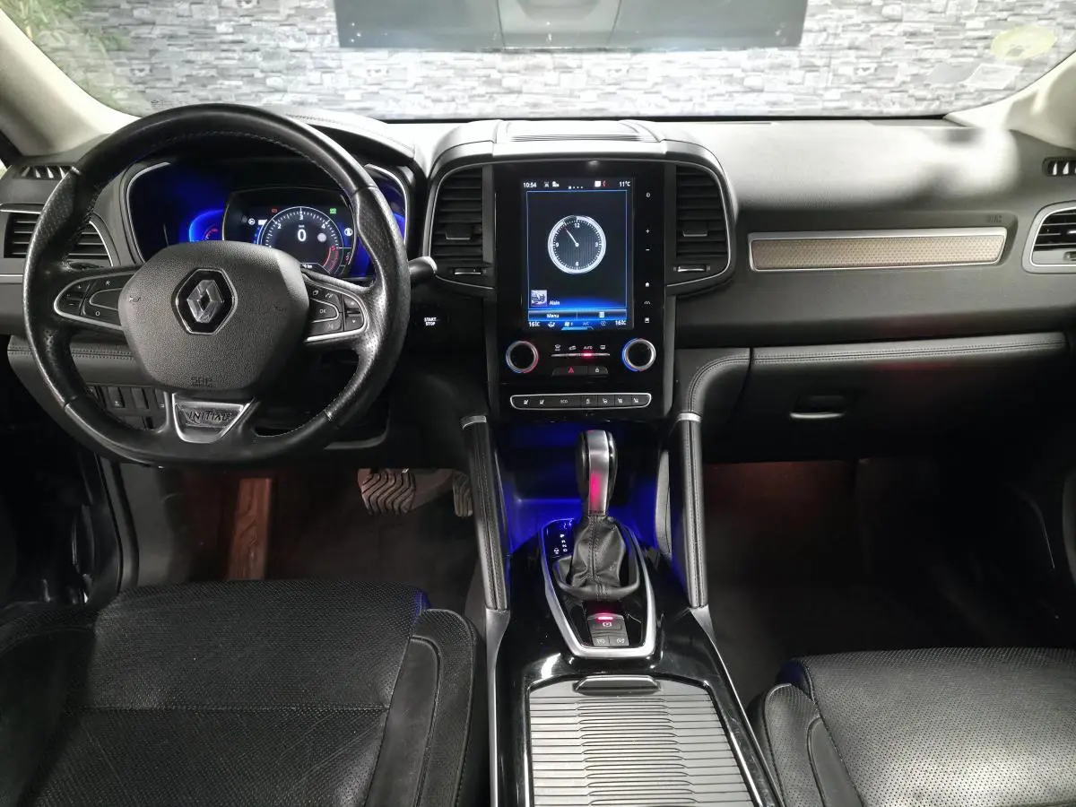 Vue intérieure avant du Renault Koleos 2017, tableau de bord noir avec écran tactile vertical et volant cuir siglé Renault.