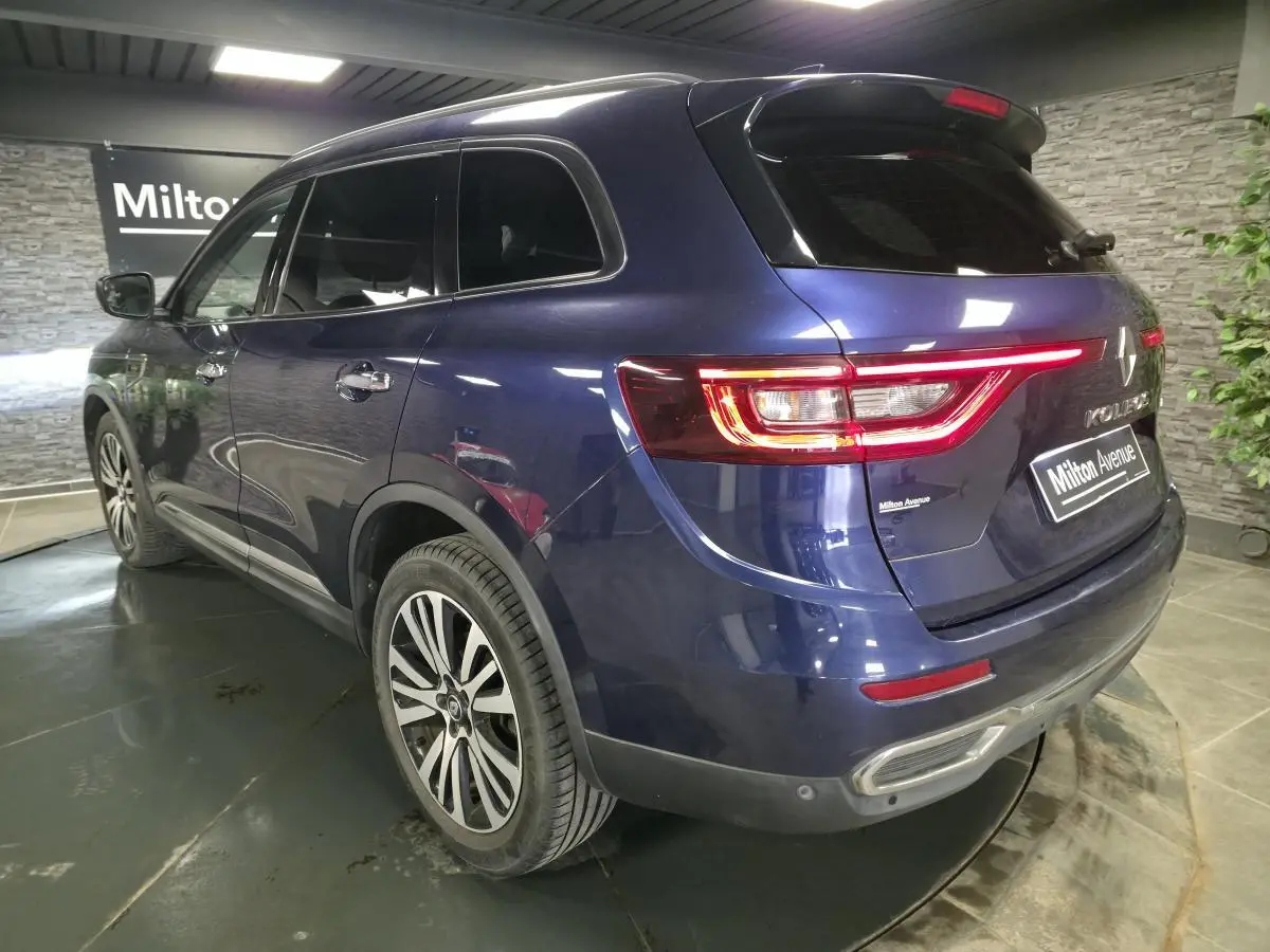 Vue 3/4 arrière droite du Renault Koleos bleu, avec feux arrière allumés et jantes alliage distinctives.