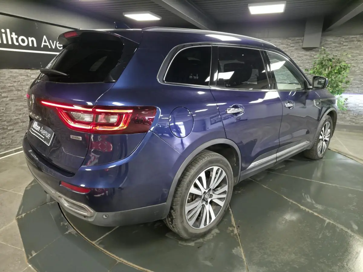 Vue 3/4 arrière droite du Renault Koleos bleu avec jantes alliage et vitres teintées dans un showroom.