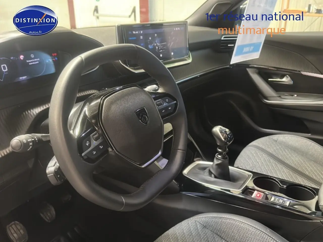 Intérieur de la Peugeot 2008 1.2 100 Allure 2025, vue côté conducteur sur volant, tableau de bord et levier de vitesse manuel.