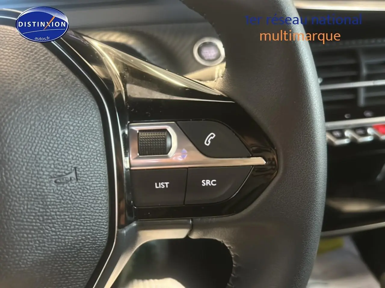 Gros plan sur les commandes gauche du volant noir du Peugeot 2008 gris artense, avec boutons multifonctions.