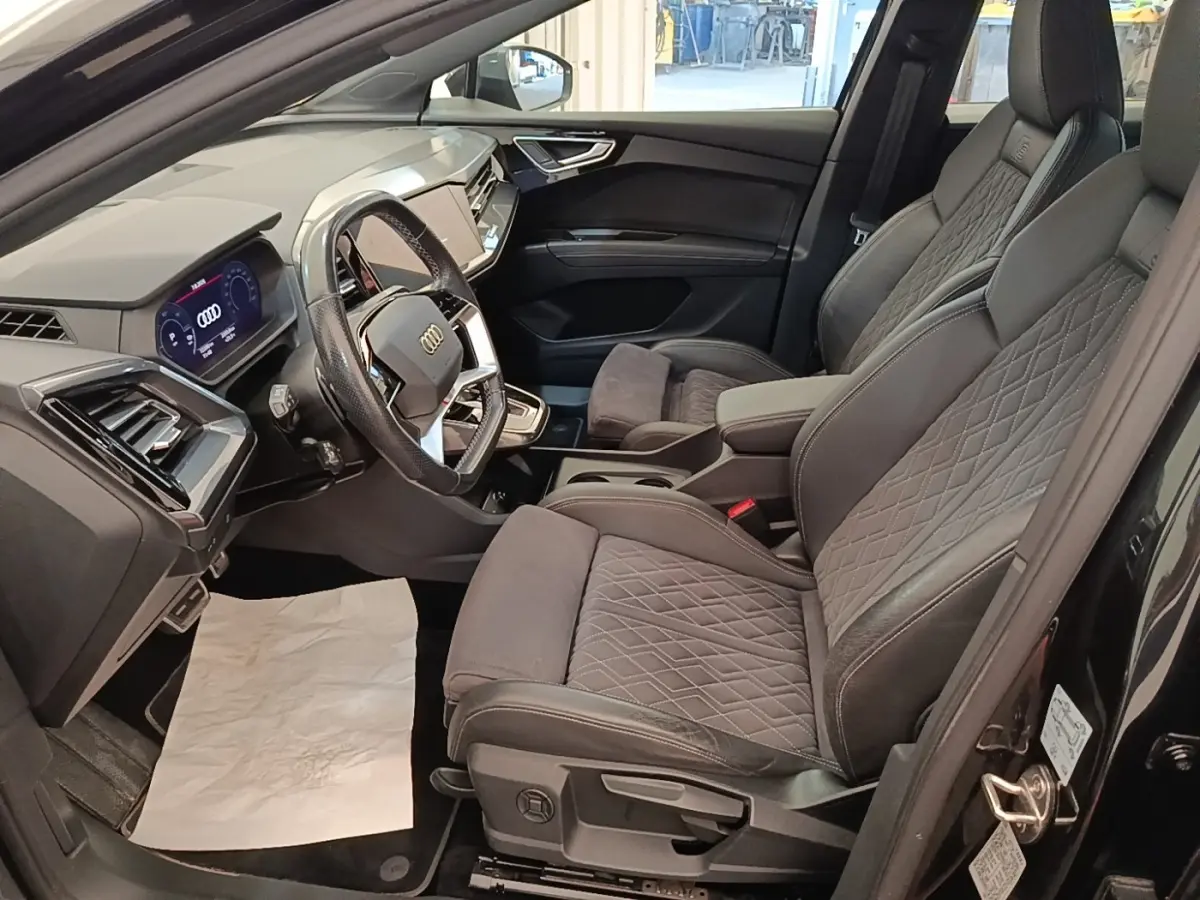 Intérieur côté conducteur de l’Audi Q4 E-TRON Sportback noir 2023, sièges S Line en cuir et alcantara, tableau de bord digital.