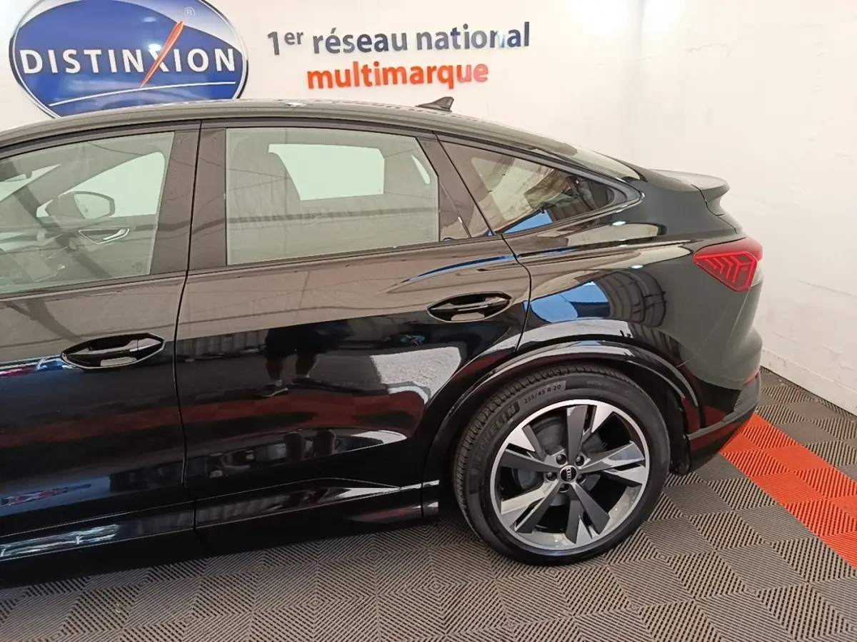 Vue latérale droite d’un Audi Q4 E-TRON Sportback noir, mettant en valeur la ligne de toit plongeante et les feux arrière LED.