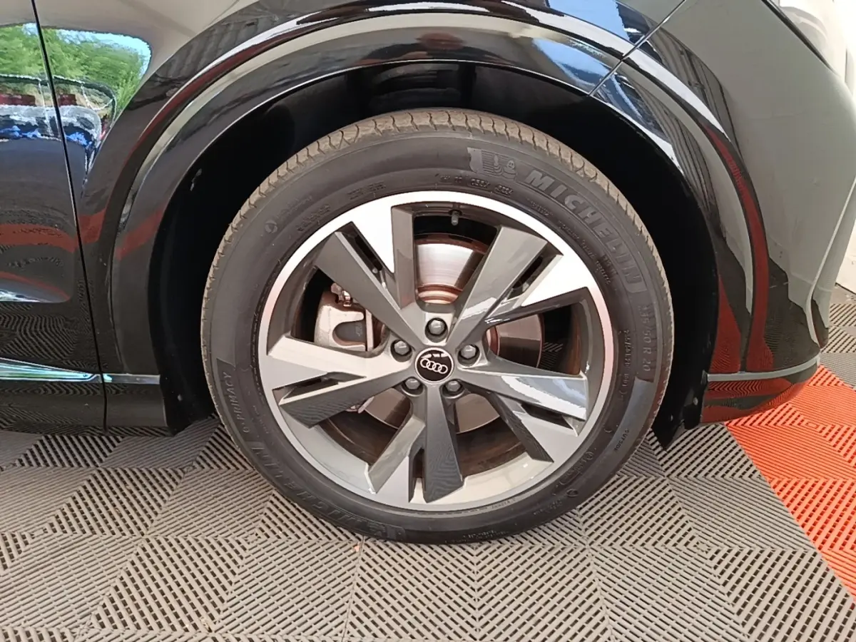 Gros plan sur la roue avant droite noire d’un Audi Q4 E-TRON Sportback électrique avec jante alliage bicolore.