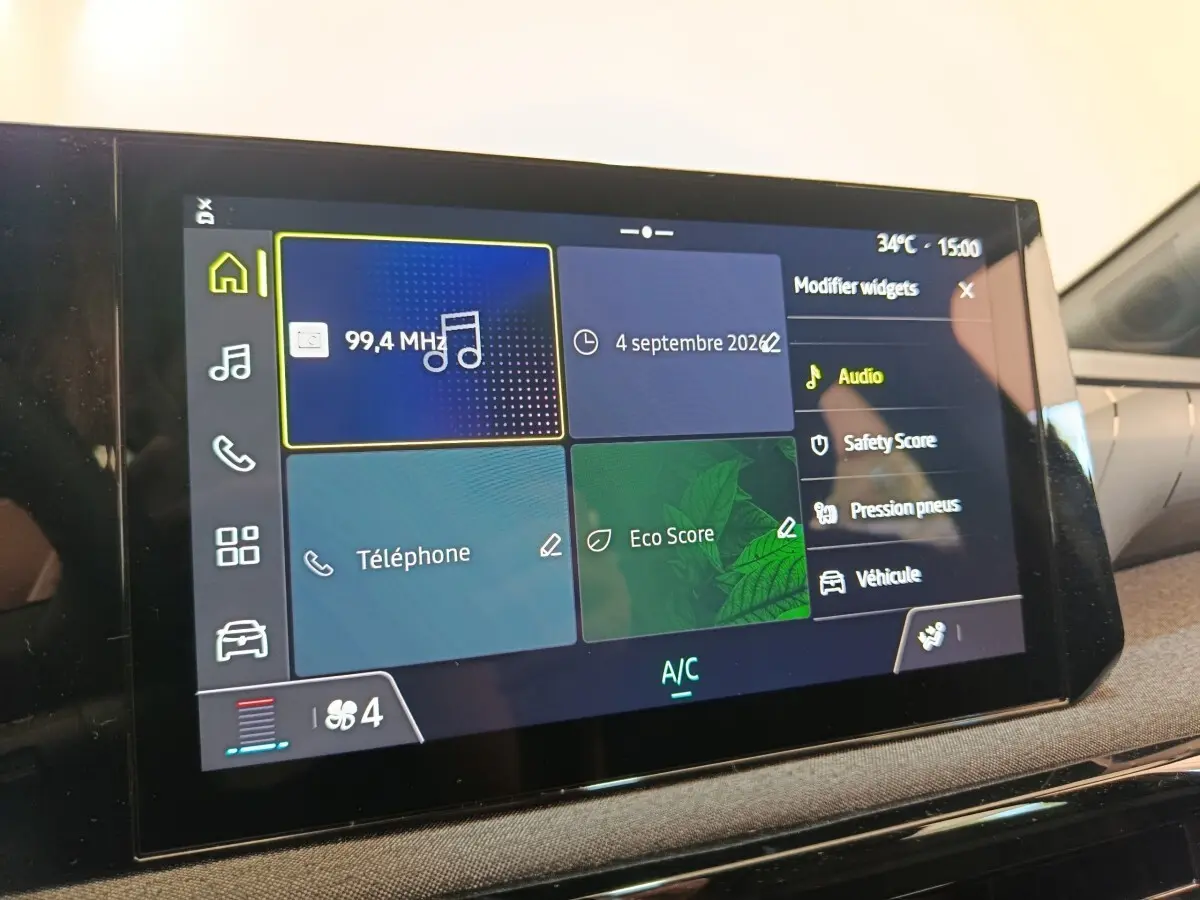Écran tactile central de la Renault Clio bleu, affichant les options audio, téléphone et score écologique en intérieur.