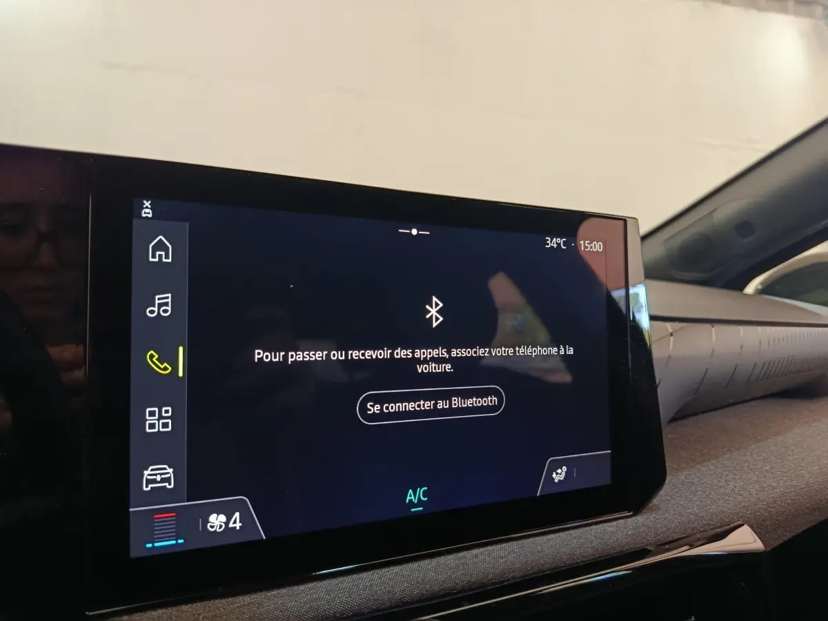Écran tactile central de la Renault Clio bleu, affichant la connexion Bluetooth dans l'habitacle côté droit.