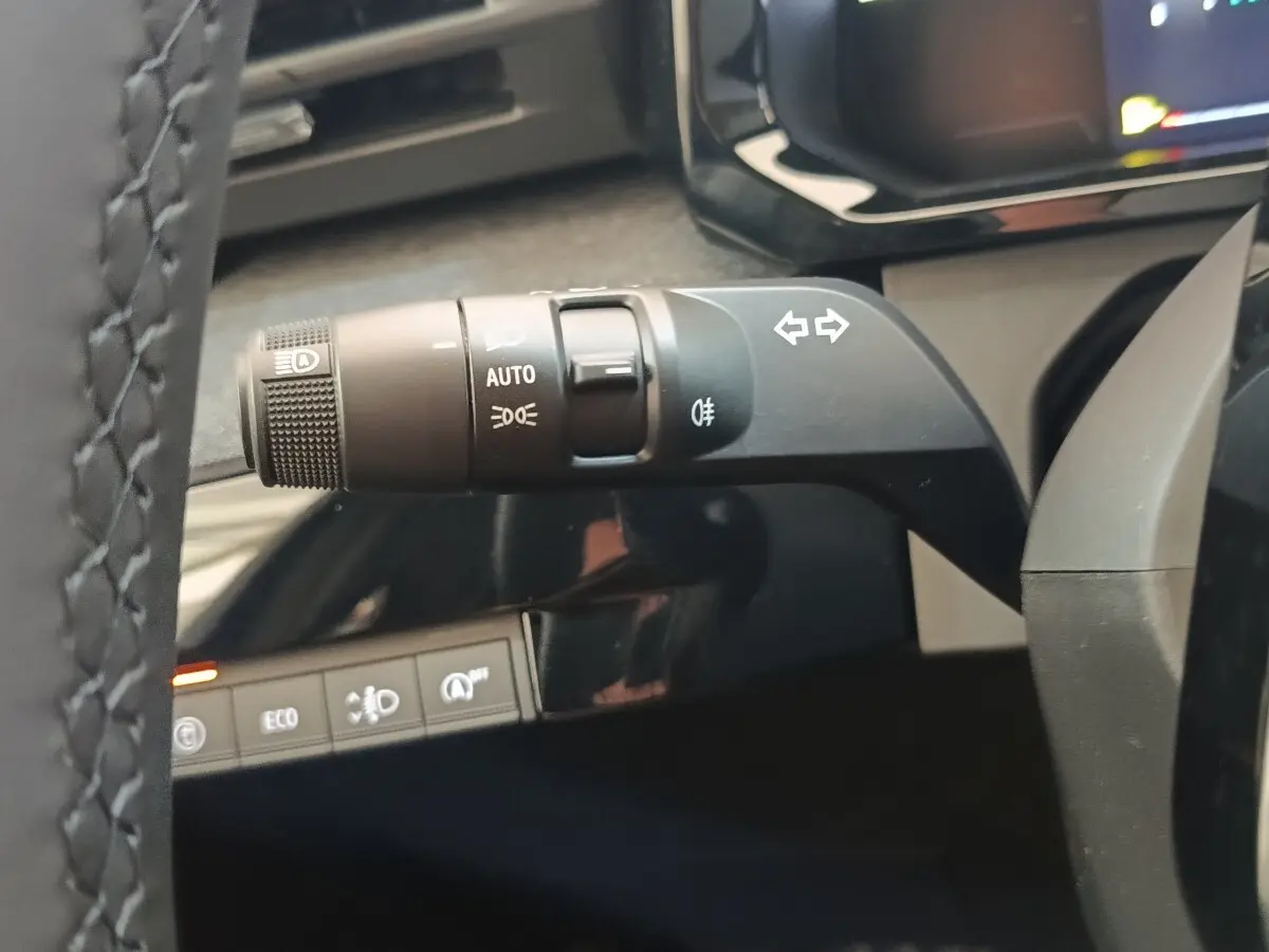 Gros plan sur la commande de clignotants et feux automatiques du volant de la Renault Clio bleu, intérieur moderne.