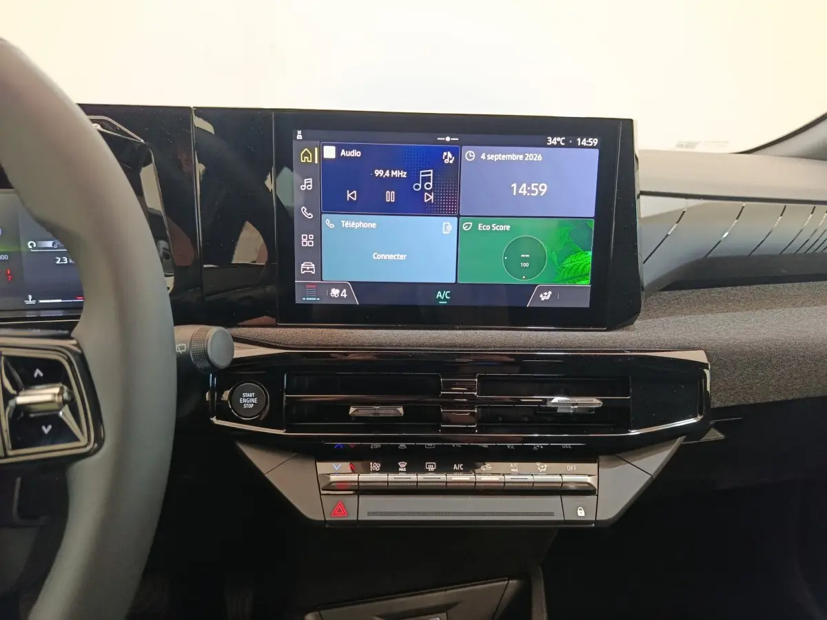 Vue intérieure centrée sur le tableau de bord noir brillant et l'écran tactile multifonctions de la Renault Clio bleu.