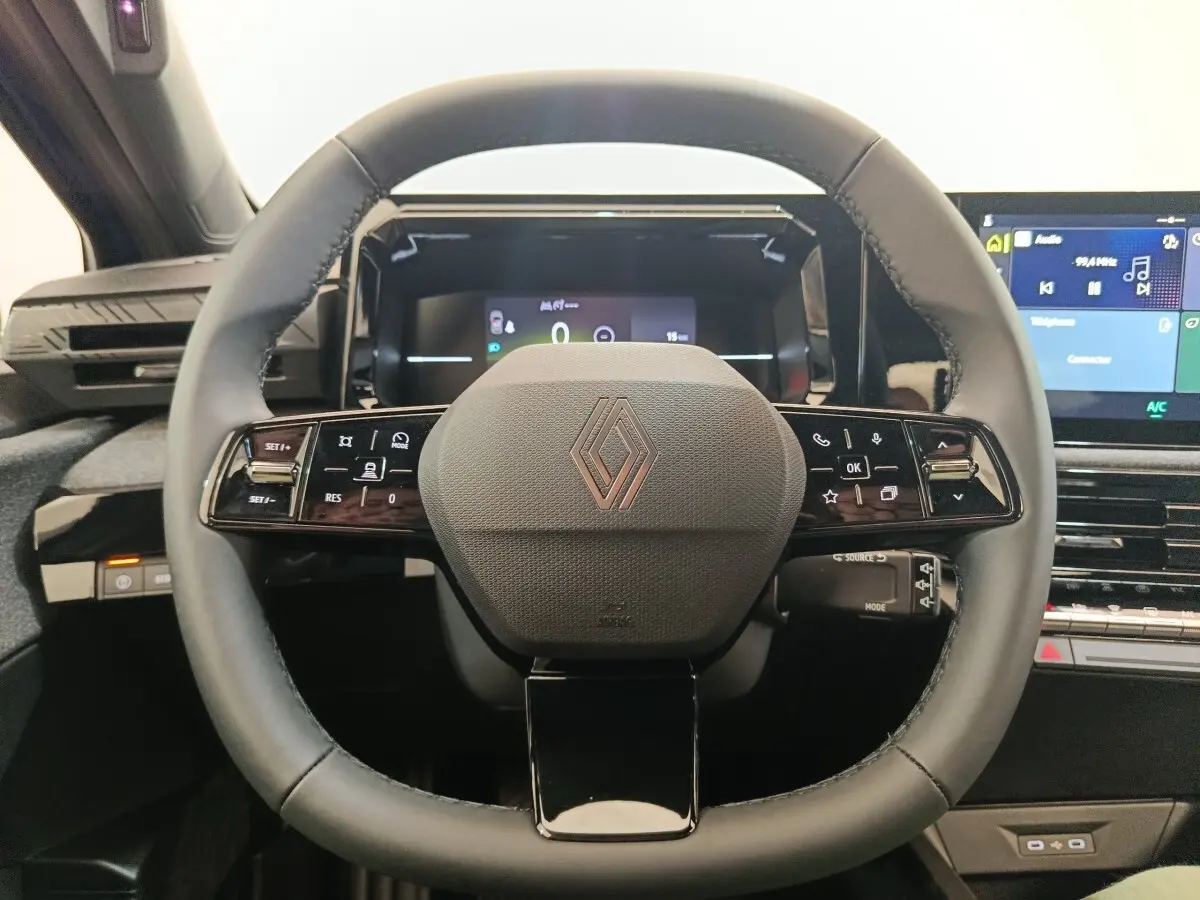 Vue rapprochée du volant multifonctions noir de la Renault Clio 2026 avec tableau de bord digital et écran central tactile.