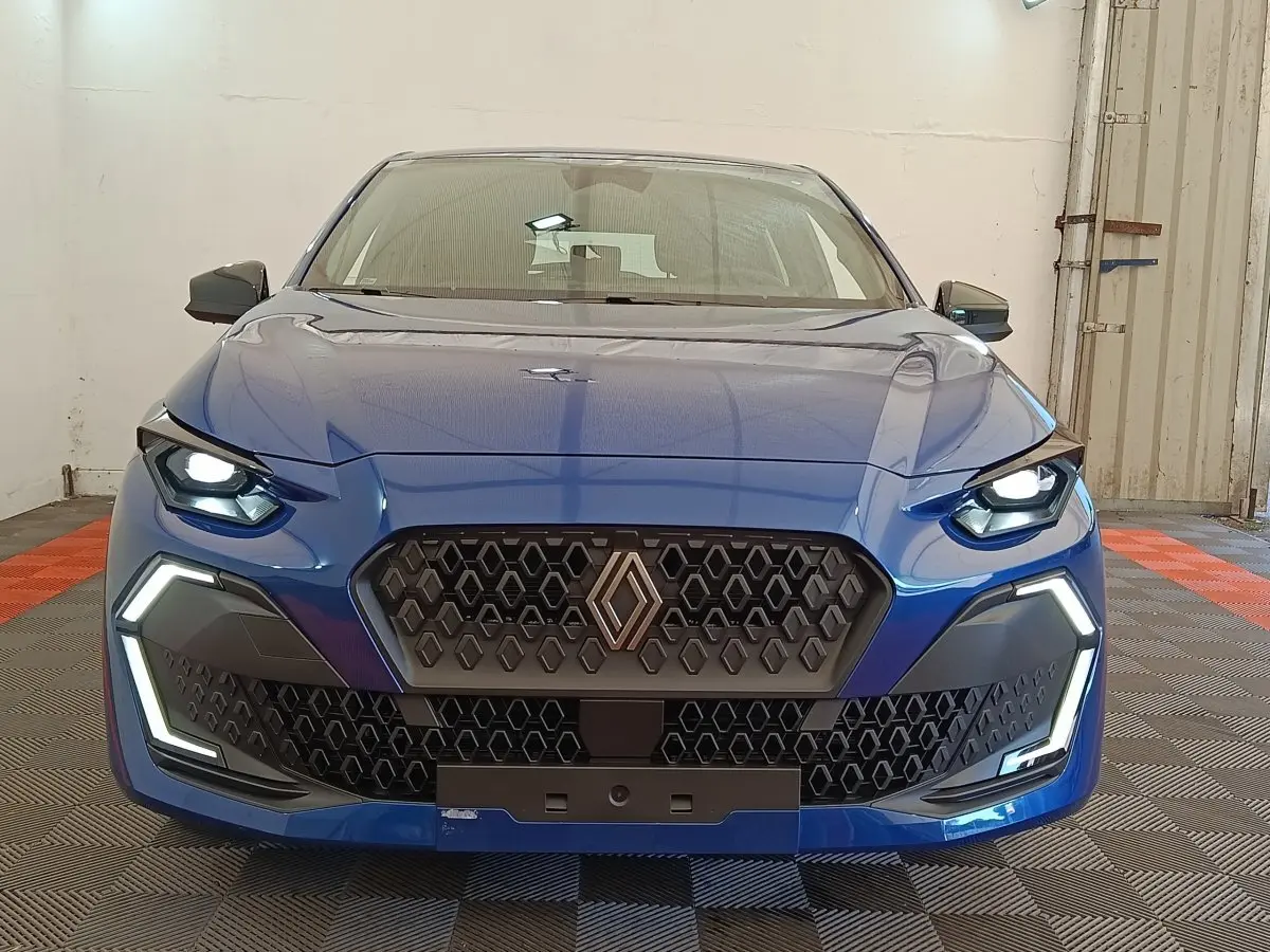 Vue frontale d'une Renault Clio Evolution TCe 115 bleu avec calandre hexagonale et feux LED allumés.