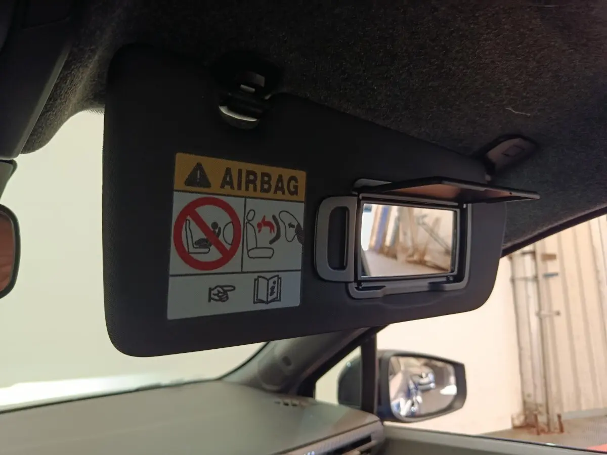 Détail du pare-soleil côté conducteur avec miroir intégré et avertissement airbag dans une Renault Clio bleu 2026.