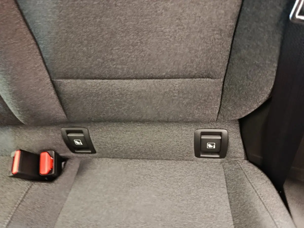 Détail de la banquette arrière grise de la Renault Clio avec fixation Isofix et boucle de ceinture rouge visible.