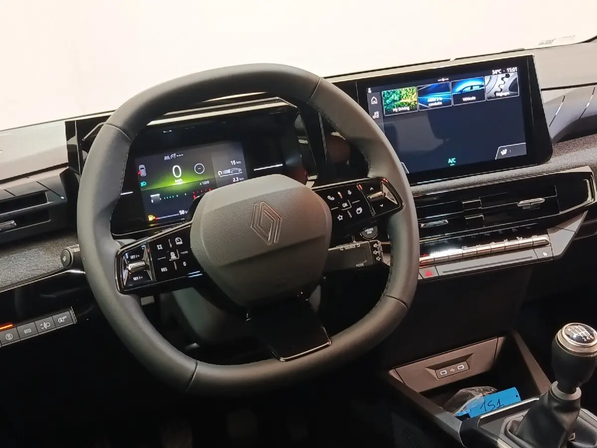 Vue rapprochée du volant multifonctions noir et du tableau de bord numérique de la Renault Clio bleu essence 2026.