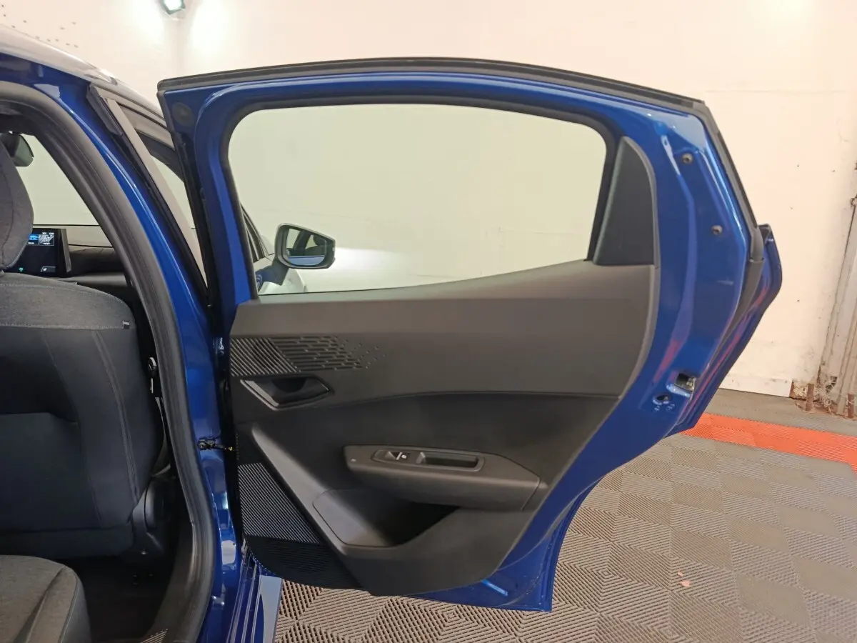 Vue intérieure de la porte arrière droite bleu de la Renault Clio 2026, avec habillage noir et commandes de fenêtre.