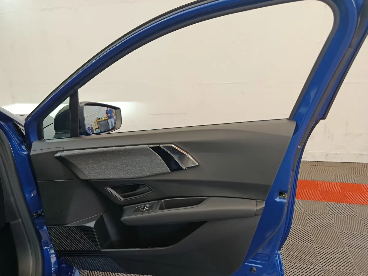 Vue intérieure de la porte avant gauche bleu Renault Clio 2026, avec garniture grise et commandes de vitre intégrées.