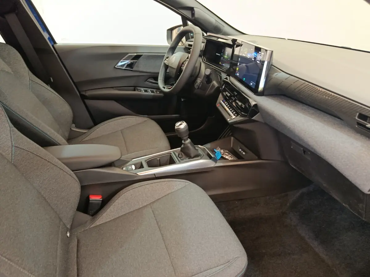 Intérieur avant droit de la Renault Clio bleu 2026, avec tableau de bord numérique et boîte manuelle visible.