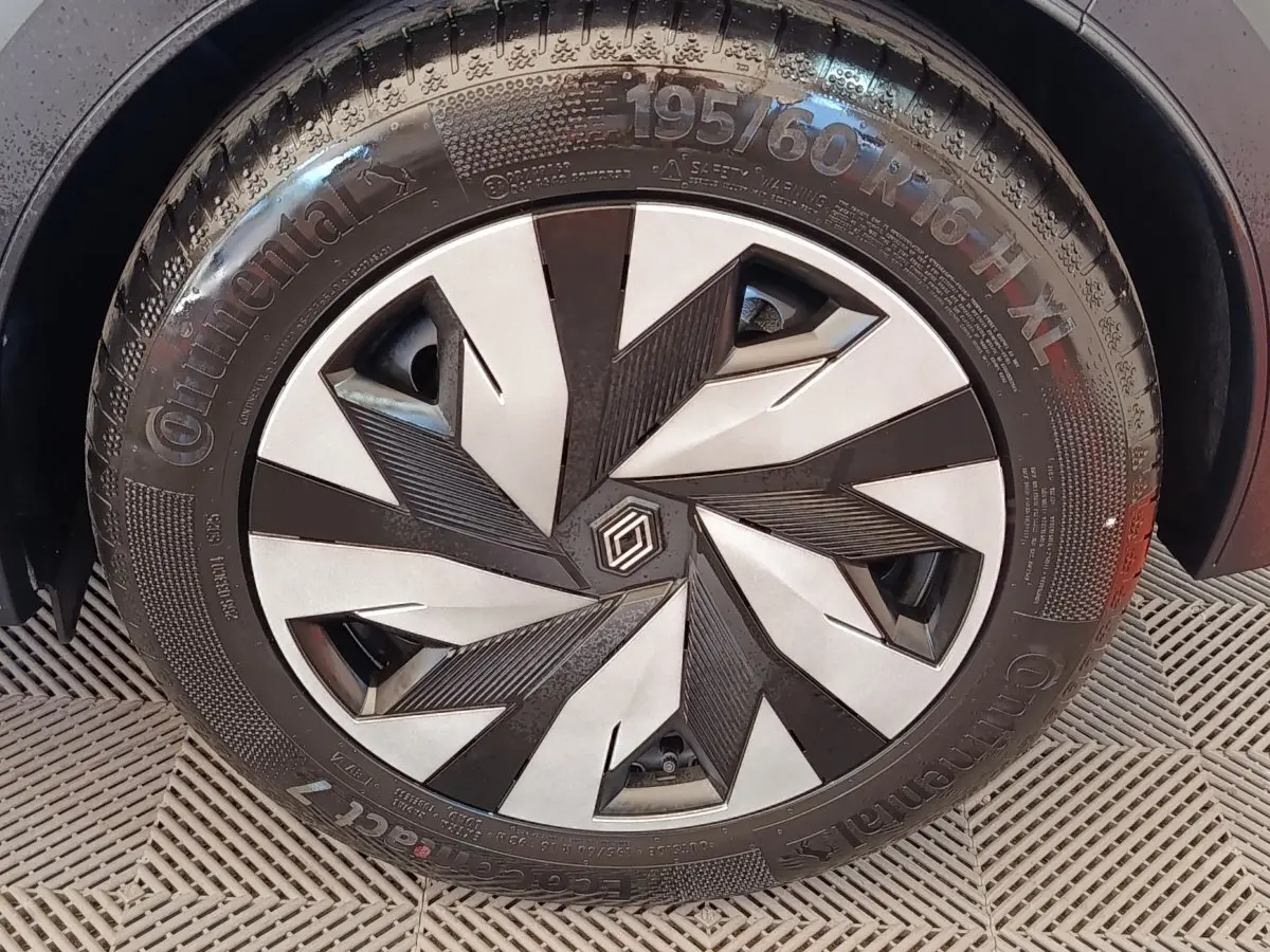 Gros plan sur la roue avant droite de la Renault Clio bleu, avec jante au design géométrique noir et argent.