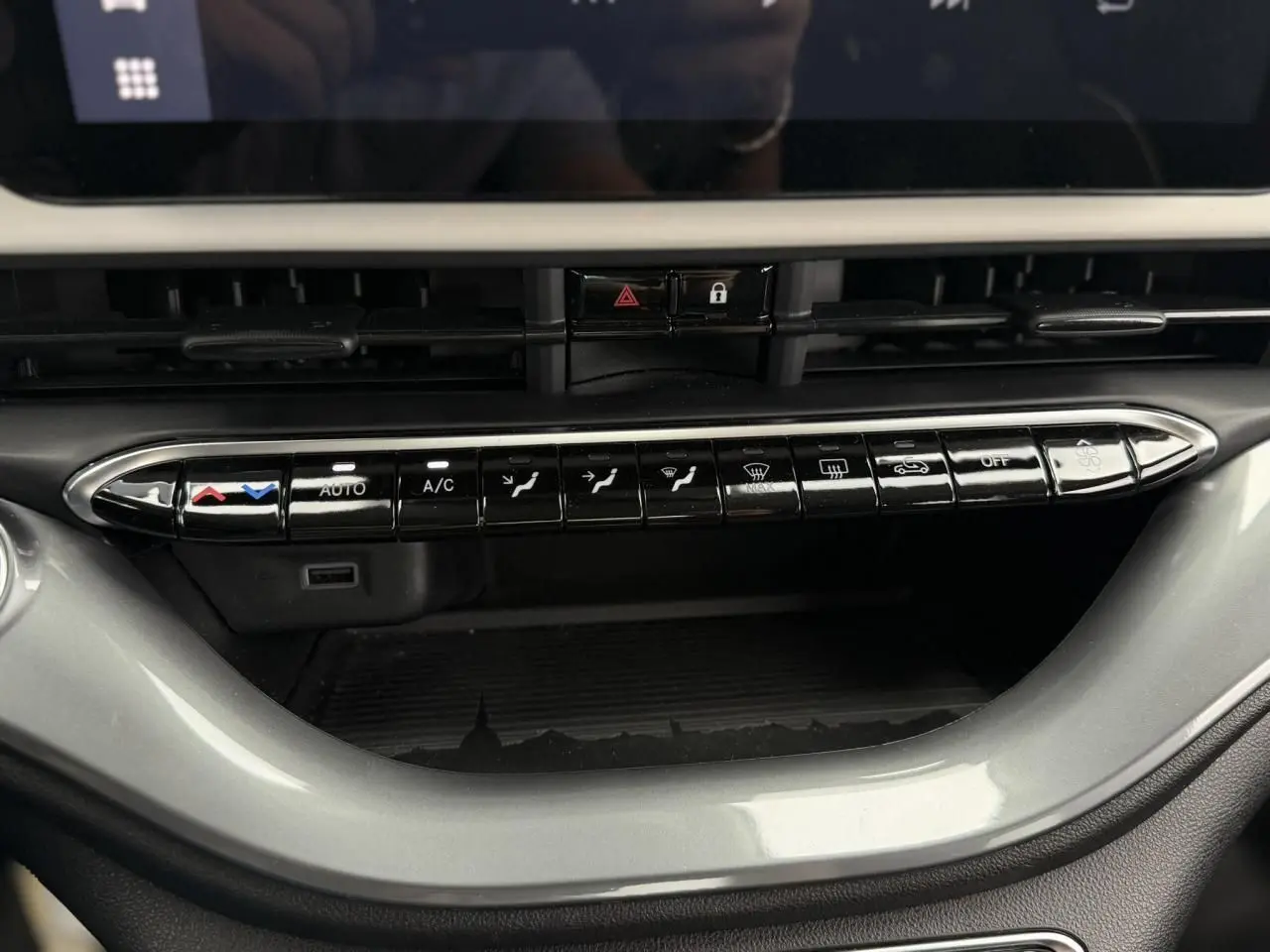 Gros plan sur la console centrale de la Fiat 500 électrique blanche 2023, montrant les commandes de climatisation et ventilation.