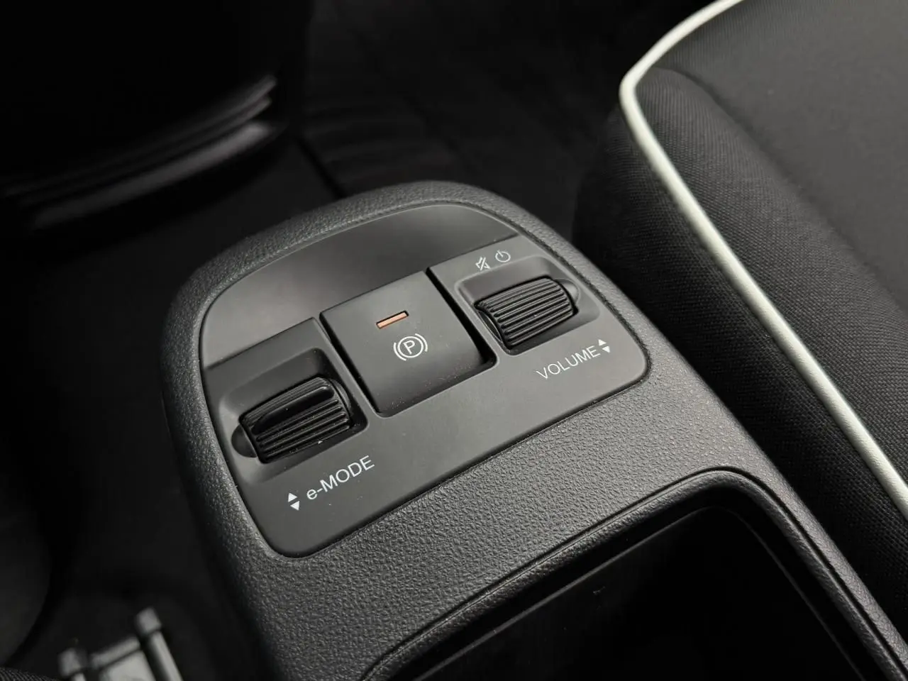 Gros plan sur la console centrale de la Fiat 500 électrique 2023, montrant les commandes e-Mode, frein à main et volume.