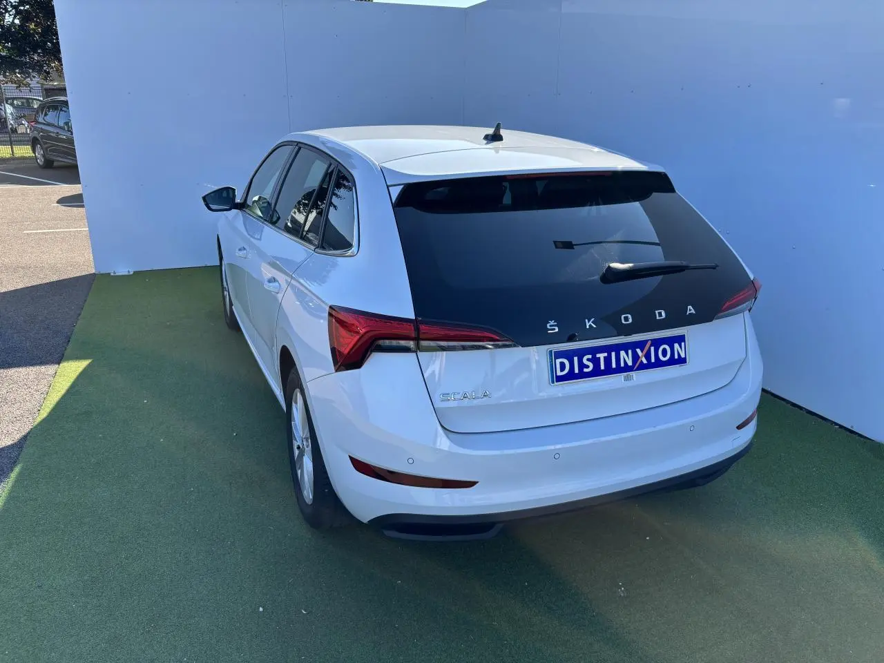 Vue 3/4 arrière droite d'une Skoda Scala blanche Glacier avec vitres arrière teintées et feux LED distinctifs.