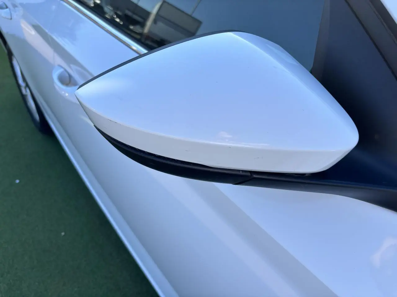 Rétroviseur blanc glacier côté gauche de la Skoda Scala 2024, avec carrosserie et poignée de porte visibles.