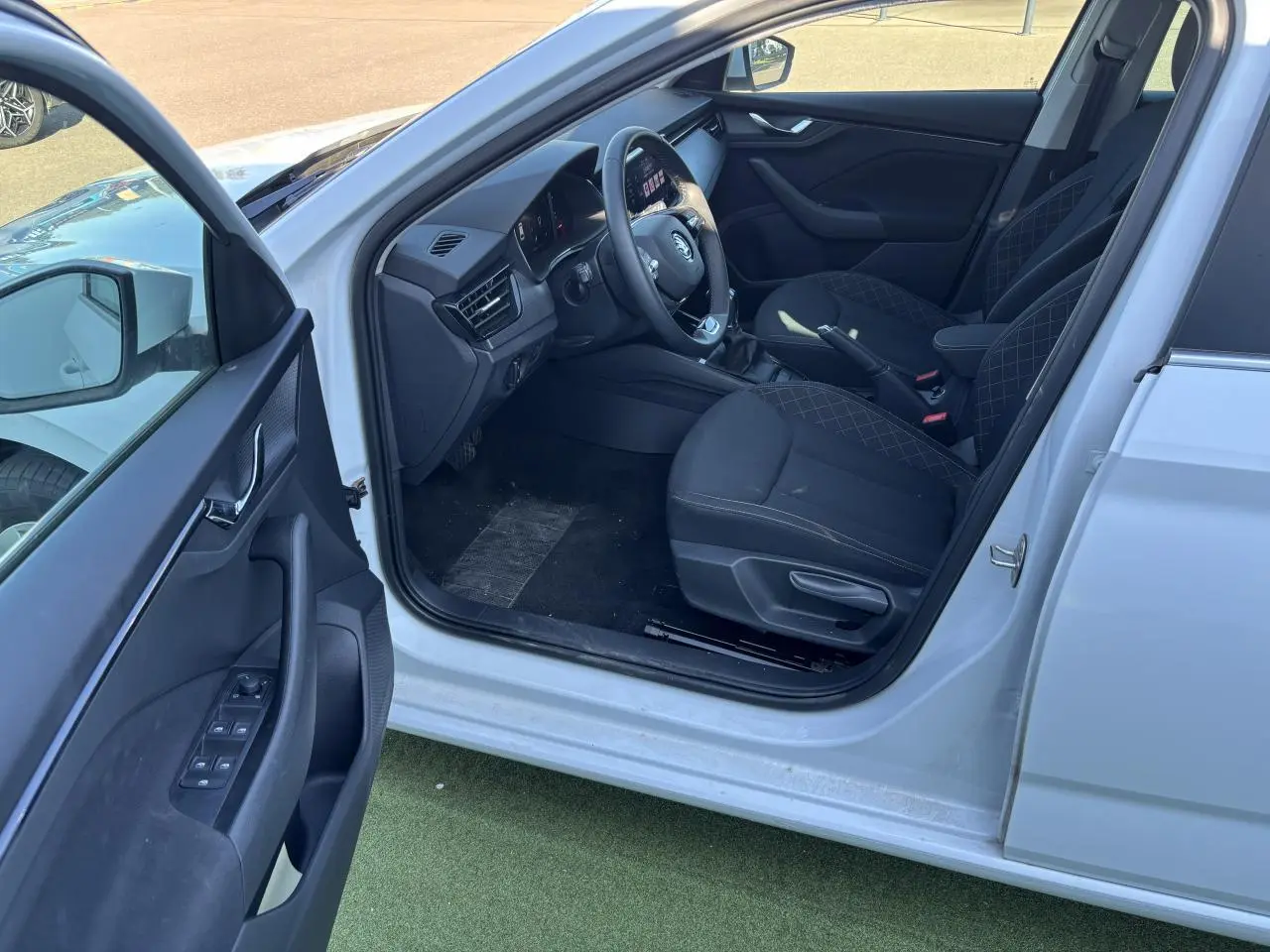 Intérieur côté conducteur d'une Skoda Scala blanc glacier 2024, montrant sièges noirs et tableau de bord moderne.
