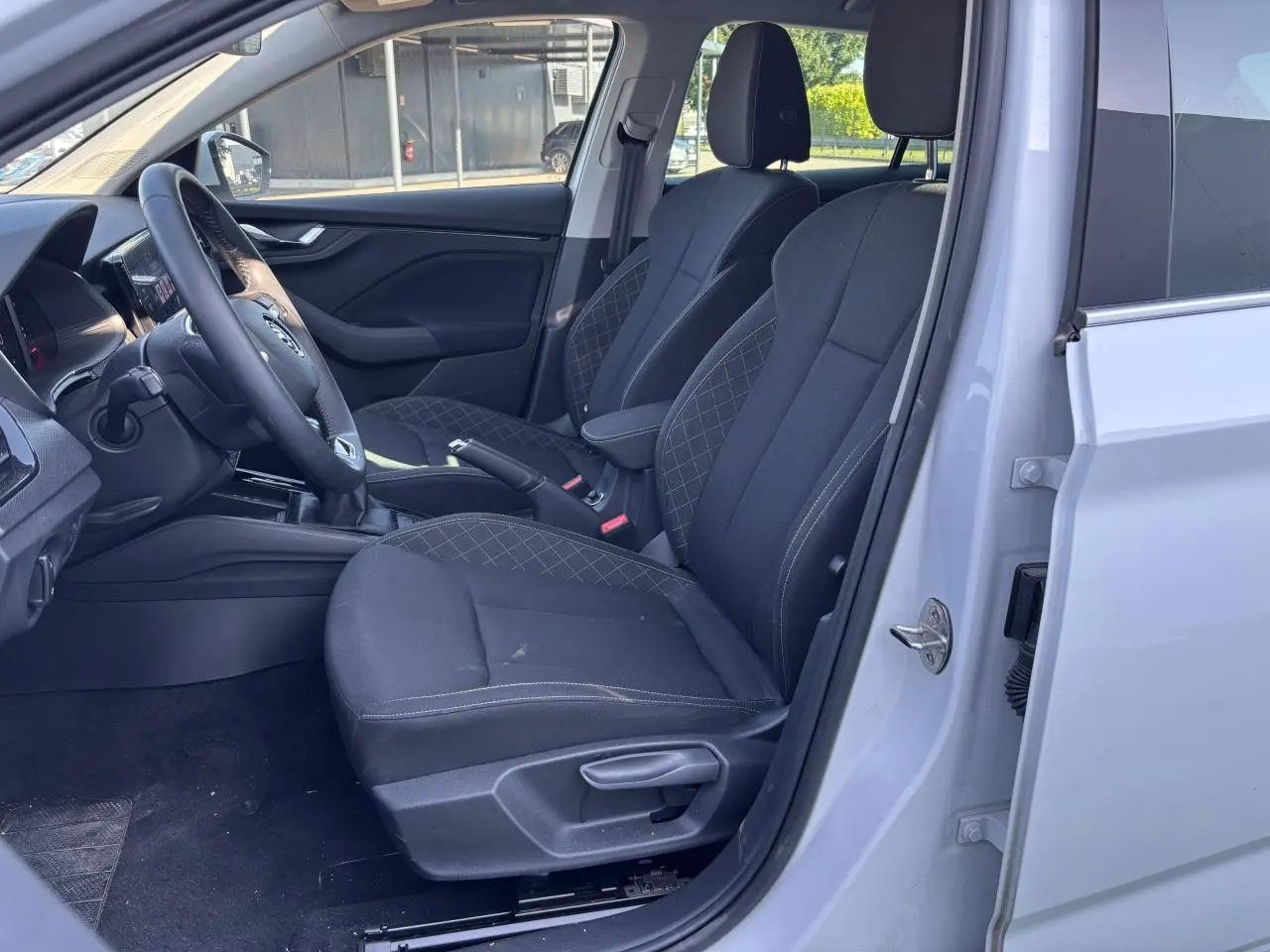Intérieur côté conducteur du Skoda Scala blanc glacier 2024, sièges noirs avec surpiqûres et volant multifonctions visible.