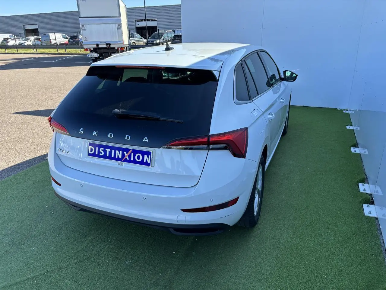 Vue 3/4 arrière droite d'une Skoda Scala blanche glacier avec feux arrière LED et vitres teintées.