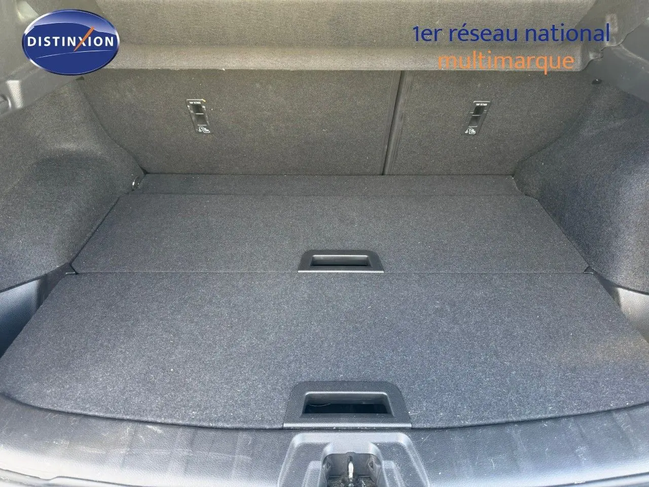 Coffre spacieux du Nissan Qashqai blanc nacré, vue plongeante montrant le plancher plat et les poignées intégrées.