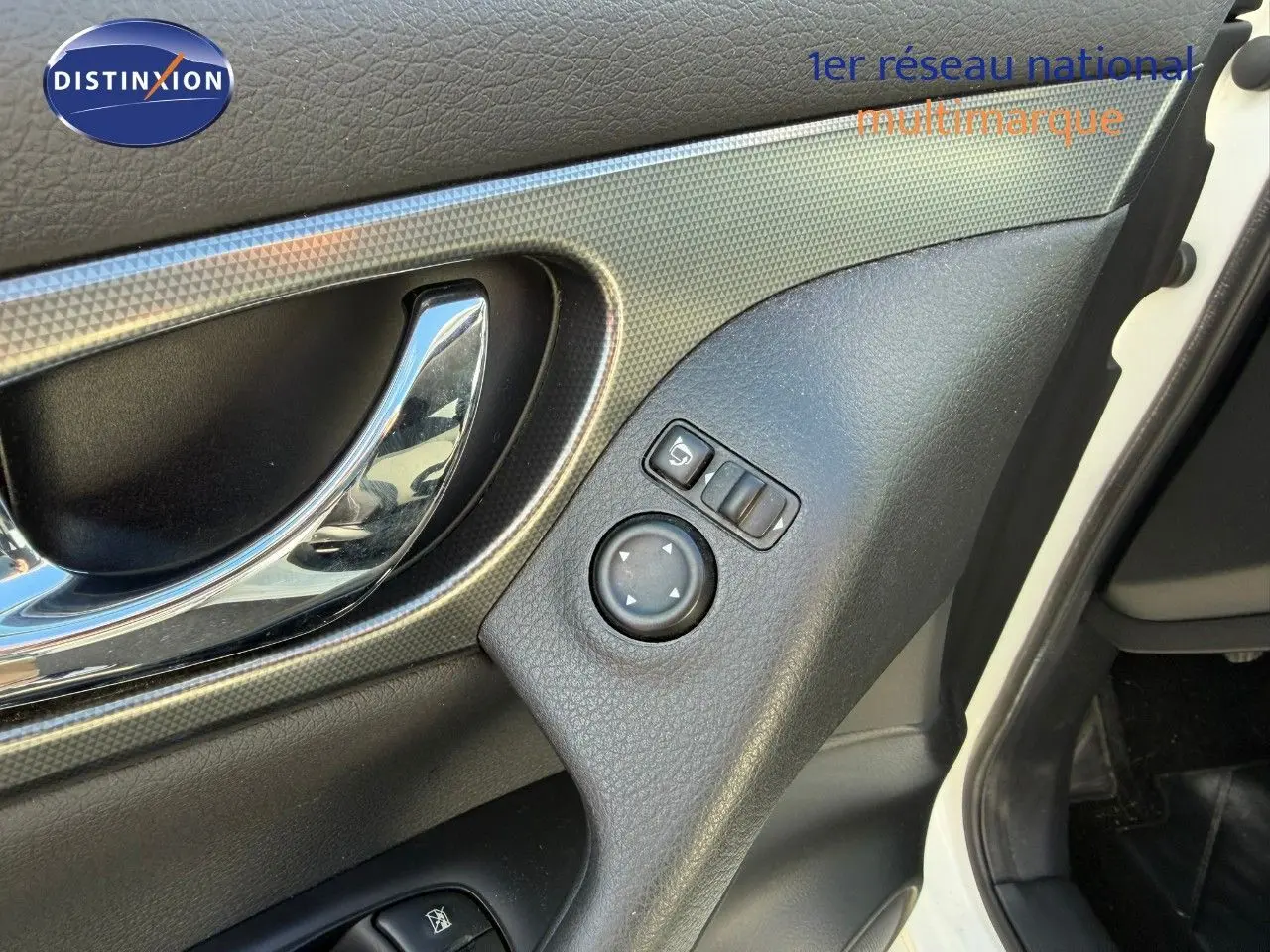 Détail de la porte avant gauche du Nissan Qashqai blanc nacré, avec poignée chromée et commandes des rétroviseurs.