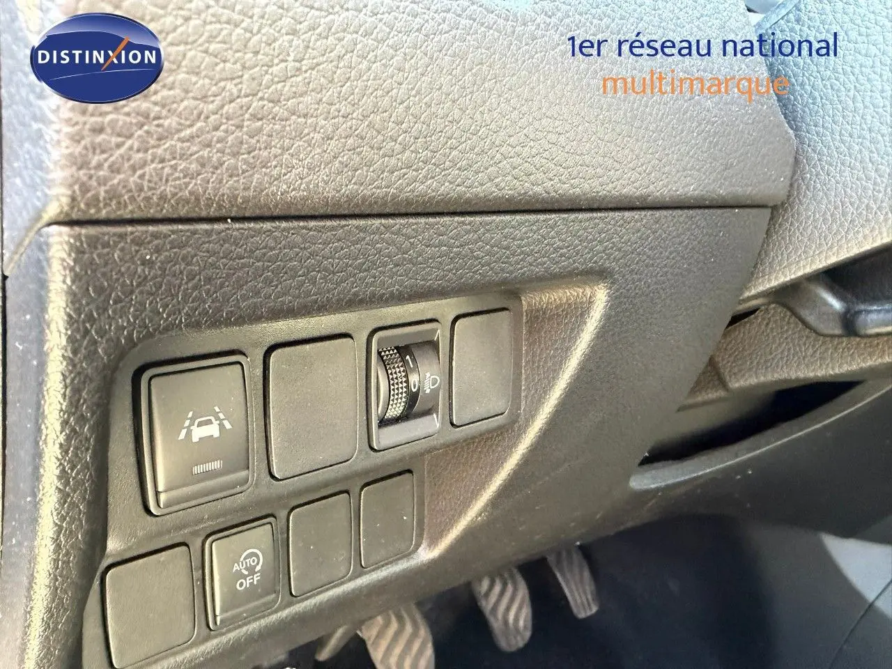 Vue intérieure du tableau de bord côté conducteur du Nissan Qashqai blanc nacré, montrant les commandes d'assistance et réglages lumineux.