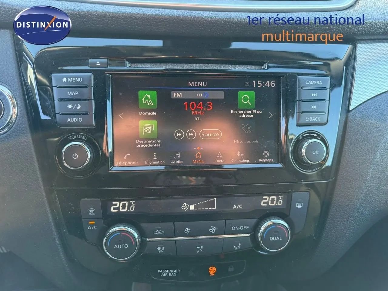 Vue rapprochée du tableau de bord du Nissan Qashqai blanc nacré, avec écran tactile et commandes de climatisation.